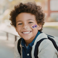 Thumbnail for smiling boy with washable tattoos of a dinosaur on his cheek