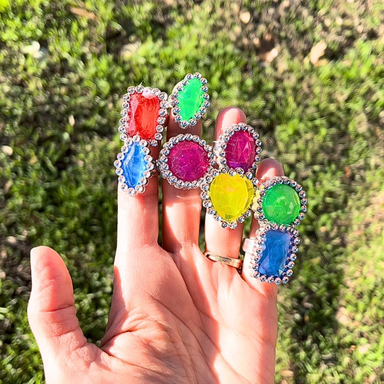 close up of bulk glamour rings on hand outside in the sunlight