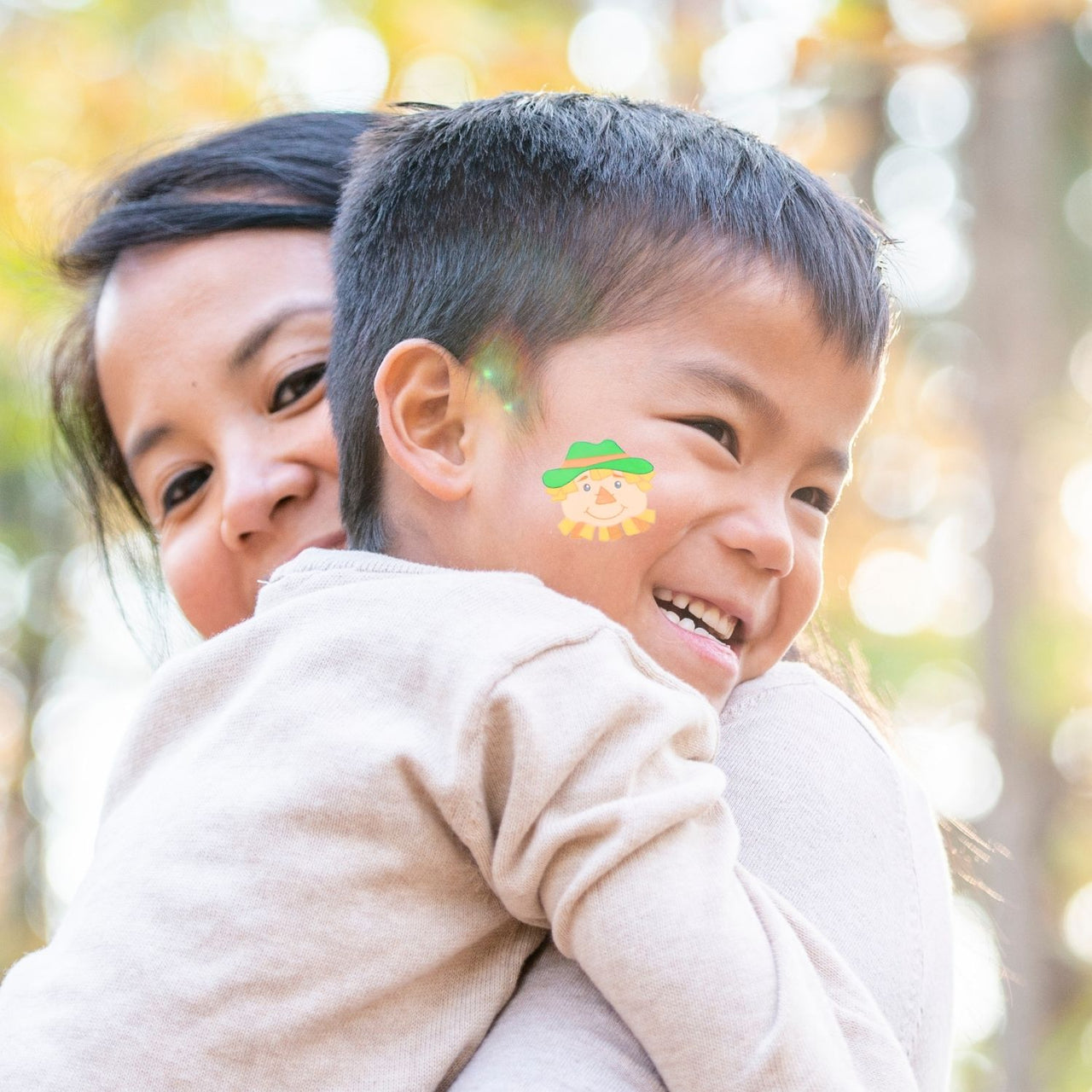 child with fall tattoo on his cheek outside with his mother