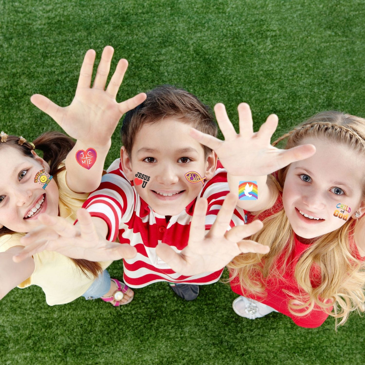 children outside with hands raised with temporary Christian tattoos