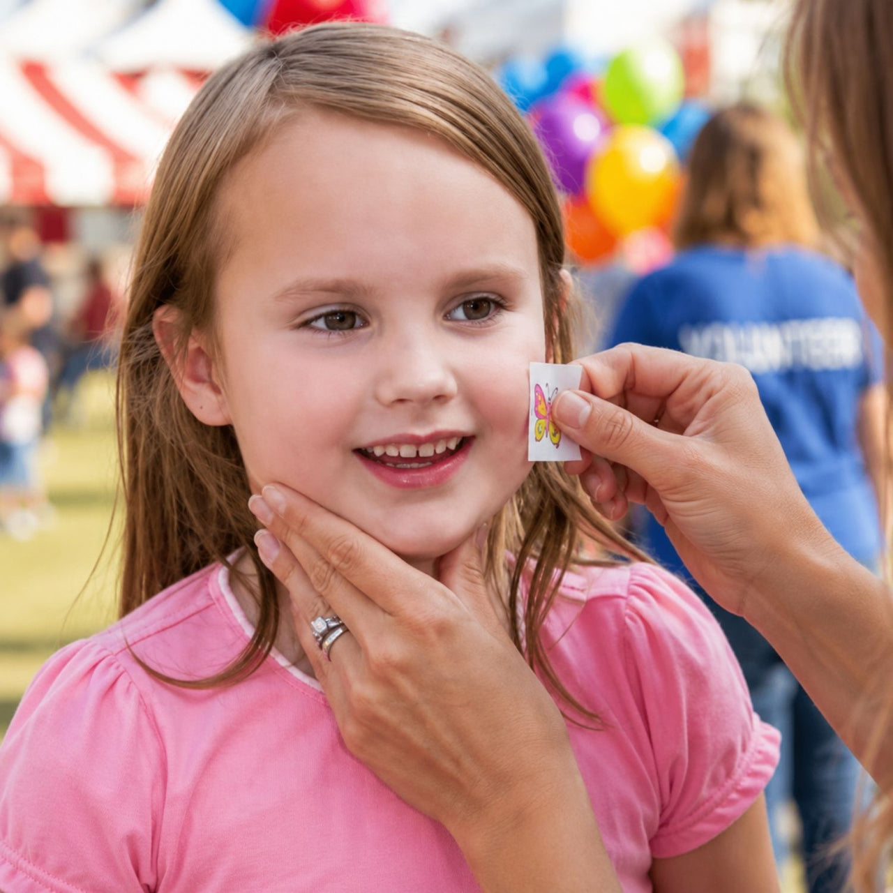 child receiving temporary tattoo at a carnival booth