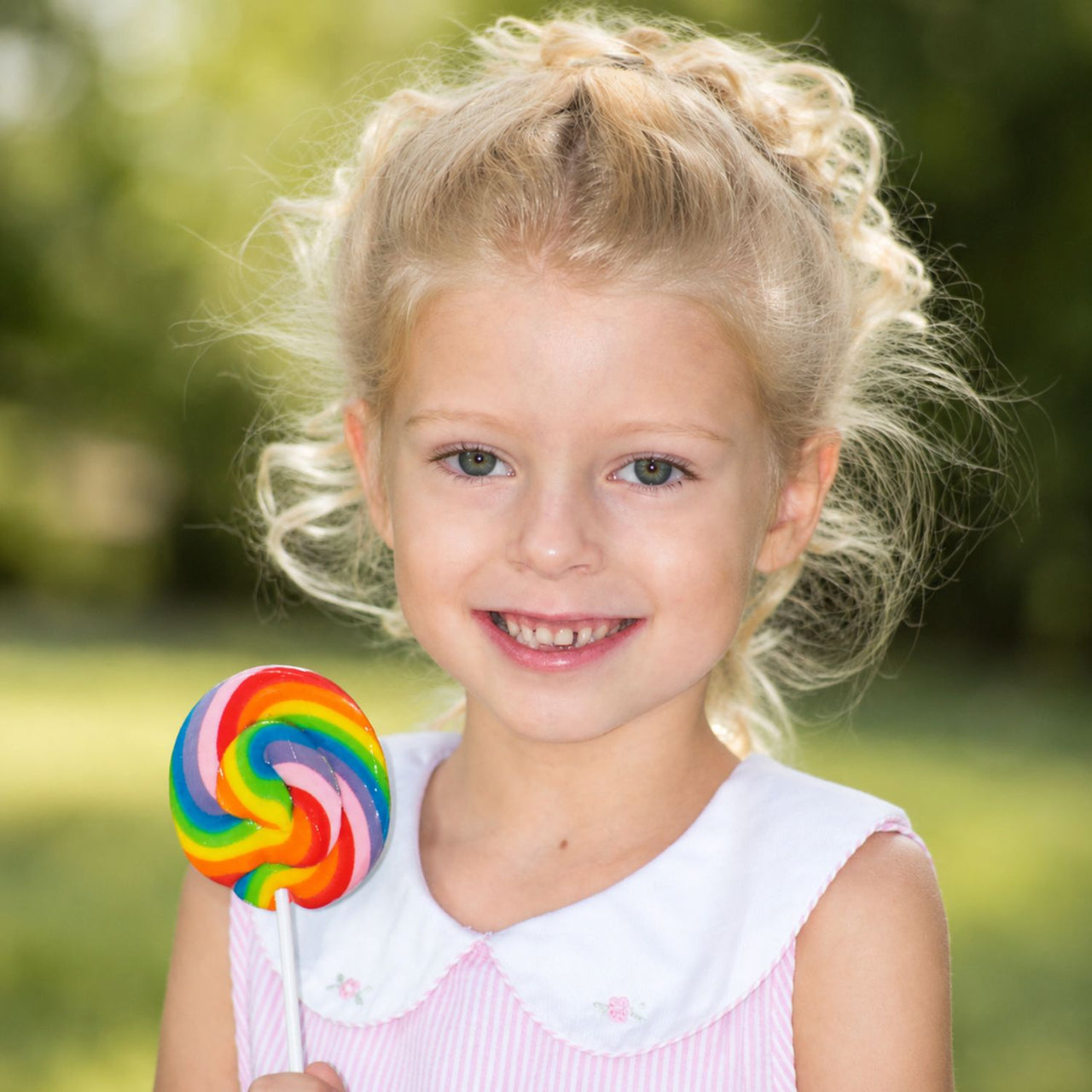 girl holding large swirl lollipop