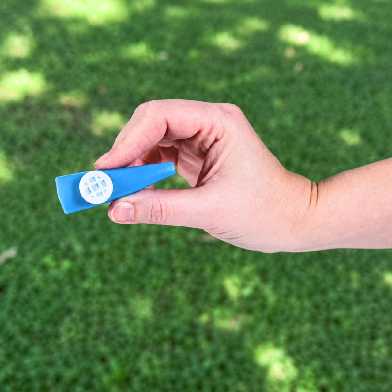 hand holding blue plastic kazoo outside