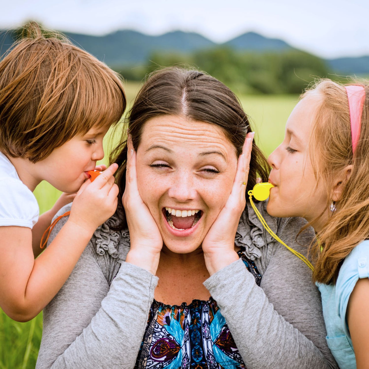 kids using whistle necklaces close to mom