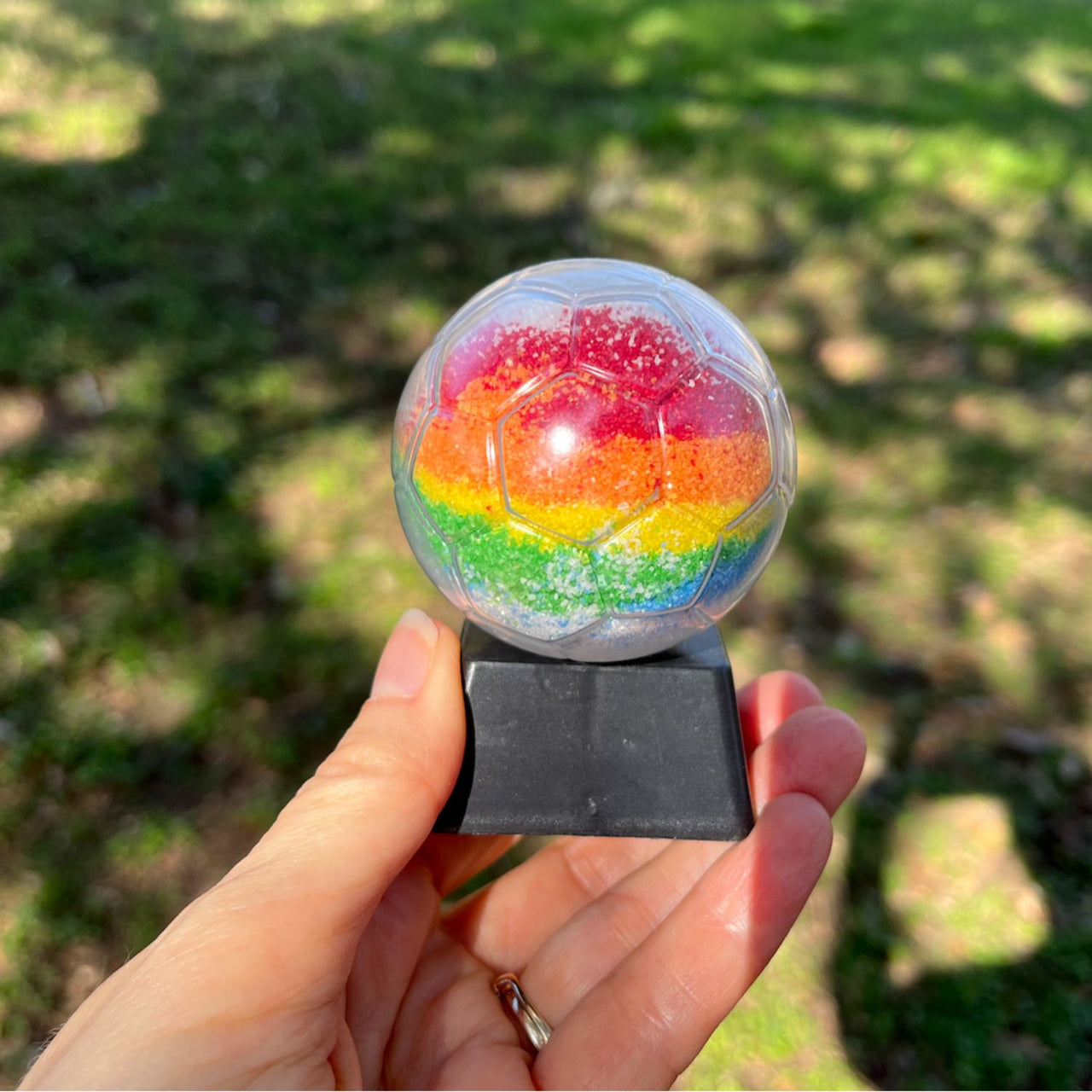 sports sand art bottle in hand with rainbow colored sand 